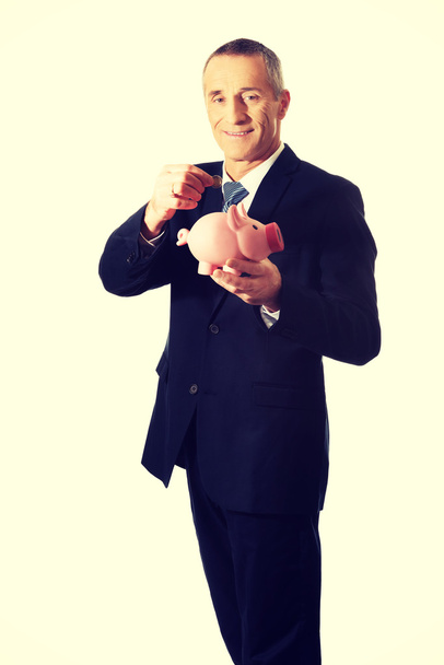 Cheerful businessman holding piggybank - Zdjęcie, obraz
