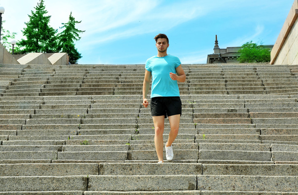 Young man jogging at stairs outdoors - Foto, imagen