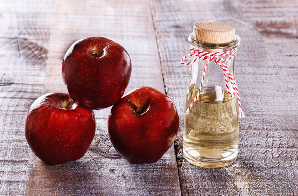 Яблочный уксус и яблоки на белом деревянном фоне
 - Фото, изображение