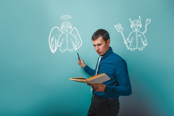 man holding a book showing an angel and devil demon infographics - Fotó, kép
