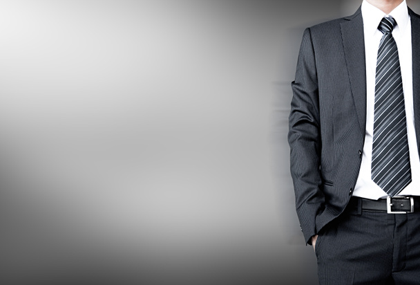 Podnikatel na sobě oblek & uvázat stojící na bílém šedé pozadí - Fotografie, Obrázek