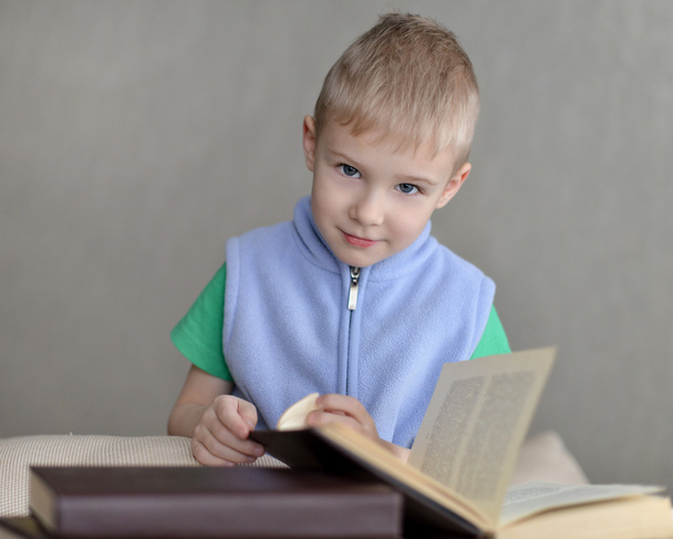 Маленький хлопчик сидить на дивані з книгою
 - Фото, зображення