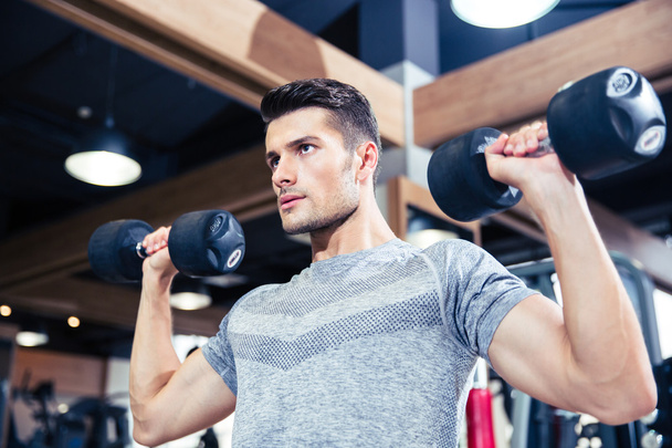 Man doing exercises with dumbbells at gym - Zdjęcie, obraz