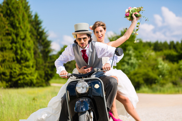 Młodej pary jazdy motor skuter na sobie suknię i komplet - Zdjęcie, obraz