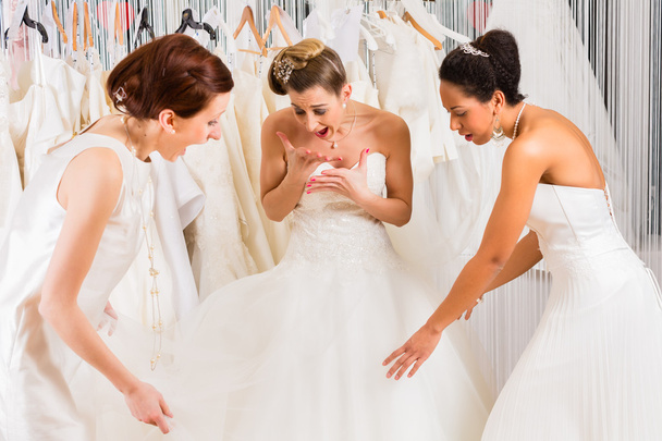 Vrouwen plezier tijdens bruids jurk montage in winkel - Foto, afbeelding