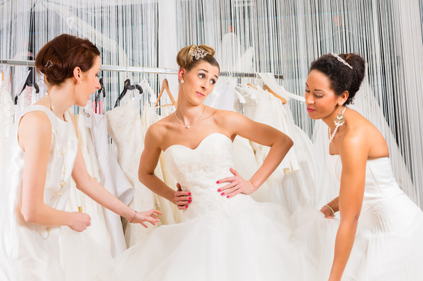 Женщины веселятся во время примерки свадебного платья в магазине
 - Фото, изображение