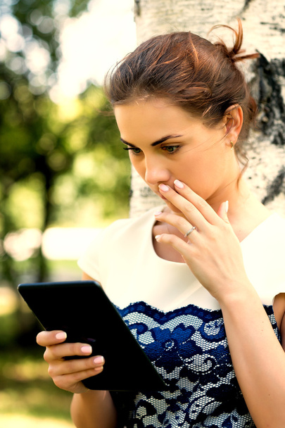 Красива дівчина з цифровим планшетом в парку
 - Фото, зображення