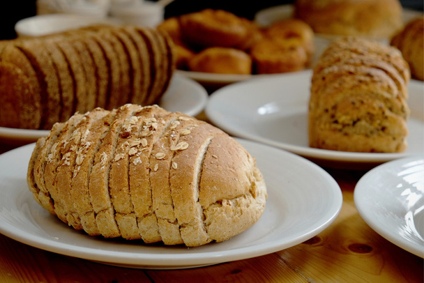 Хлеб на белой тарелке и деревянный стол
 - Фото, изображение