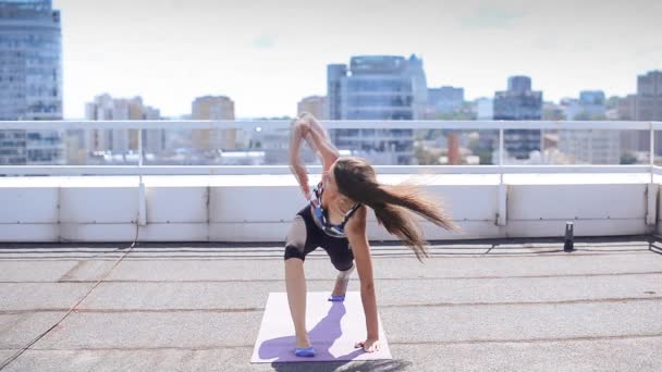 Nainen harrastaa joogaa ja pilates-harjoituksia kaupungin pilvenpiirtäjän katolla
 - Materiaali, video