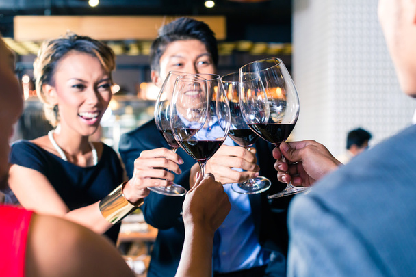 Ασίας οι φίλοι φρυγανίσματος με κόκκινο κρασί στο μπαρ  - Φωτογραφία, εικόνα