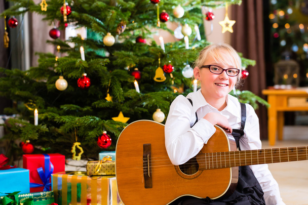 Menina tocando guitarra no dia de Natal
 - Foto, Imagem