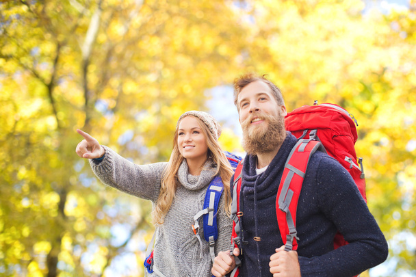 smiling couple with backpacks hiking over autumn - Fotoğraf, Görsel