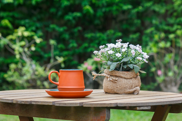Kopje koffie en bloemen met boom op achtergrond. - Foto, afbeelding