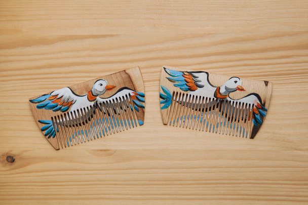 髪をとかすために木製の櫛。手作りの飛行アヒルを描いた木製の櫛. - 写真・画像
