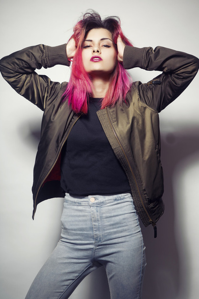 young woman in jacket and blue jeans with pink hair studio shot - Photo, Image