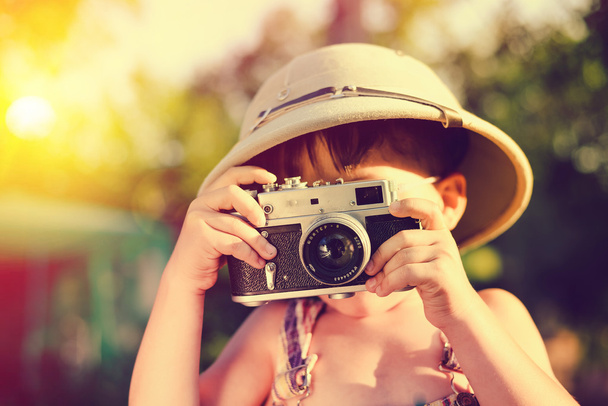 Little boy wearing pith helmet making photo with vintage camera - Foto, afbeelding
