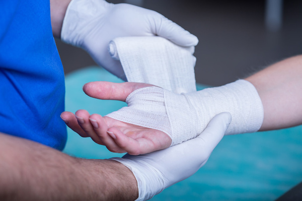male doctor bandaging a hand - Фото, зображення