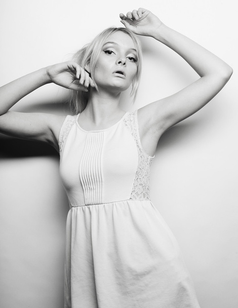  blond woman in white dress posing in studio - 写真・画像