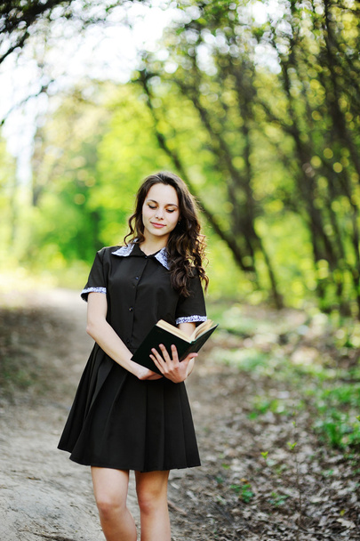 Mooie schoolmeisje met een boek in handen op een achtergrond van gre - Foto, afbeelding