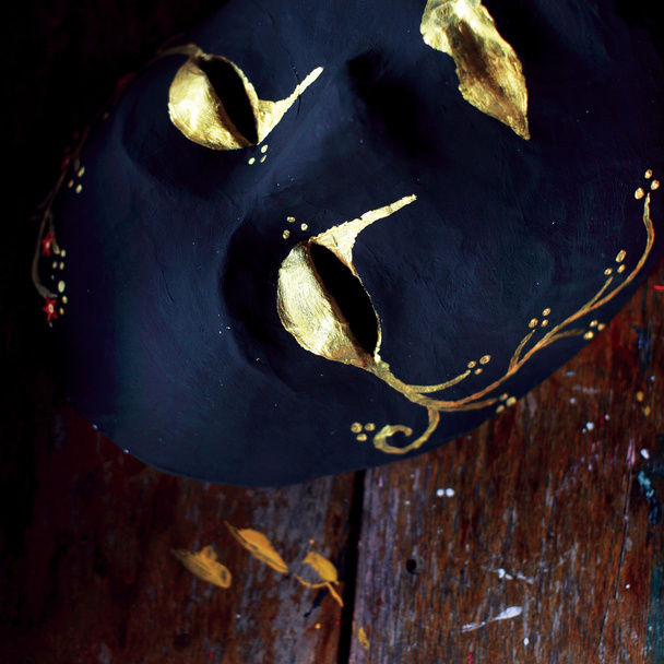 Dark full mask with golden pattern on wooden table - Photo, Image
