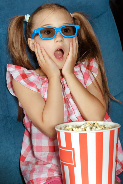 Little girl eating popcorn during a movie - Fotó, kép