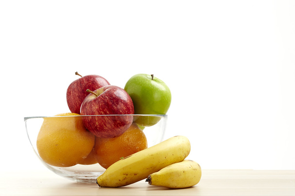 Γυάλινο μπολ με φρούτα για διατροφή για το τραπέζι από ξύλο - Φωτογραφία, εικόνα