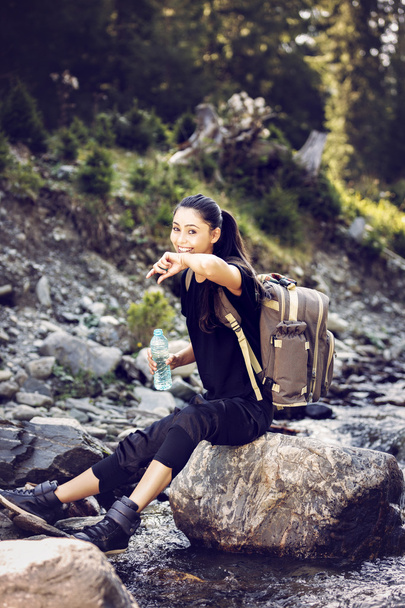 nehirdeki bir kaya üzerinde dinlenme ve su içme güzel kadın - Fotoğraf, Görsel