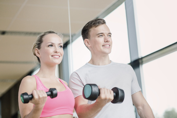 smiling young woman with personal trainer in gym - Φωτογραφία, εικόνα