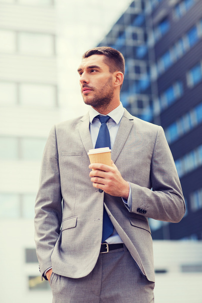 young serious businessman with paper cup outdoors - Foto, Imagem