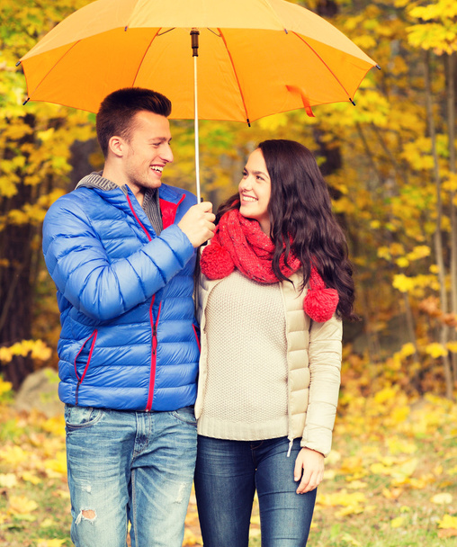 smiling couple with umbrella in autumn park - Foto, Imagen