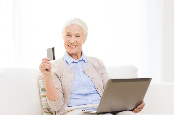 Mujer mayor con laptop y tarjeta de crédito en casa - Foto, imagen