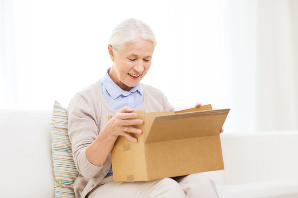 happy senior woman with parcel box at home - Foto, afbeelding