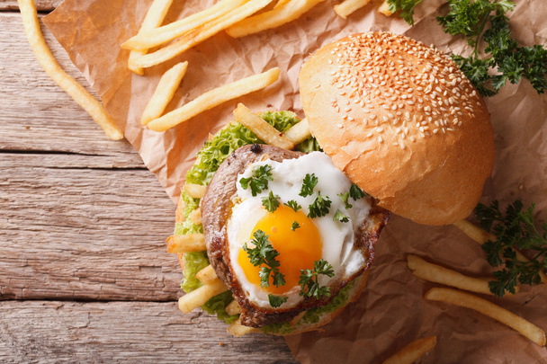 бутерброд з м'ясом на грилі, смаженим яйцем та картоплею фрі. горизонтальний до
 - Фото, зображення