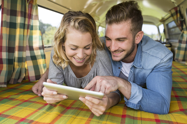 young couple with vintage camper van using touchpad - Foto, immagini