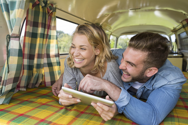 young couple with vintage camper van using touchpad - Foto, Imagem
