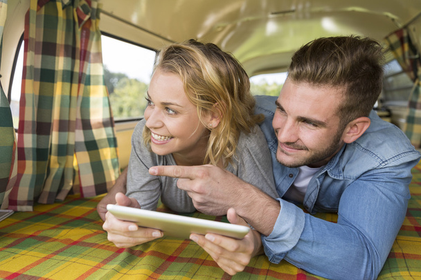 young couple with vintage camper van using touchpad - Photo, image