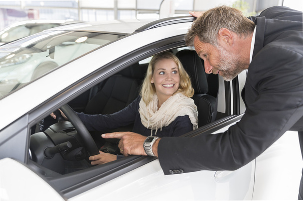 Car dealer showing vehicle binnacle to clients - Zdjęcie, obraz