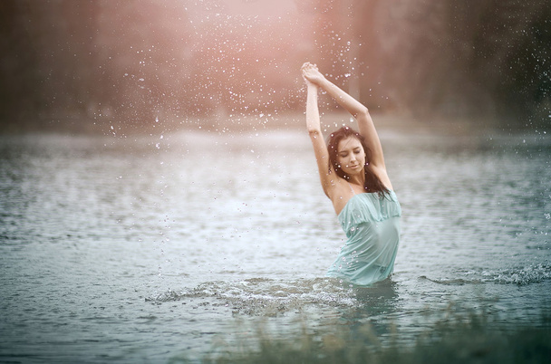 Girl splashing water in lake by her hands. Motion of  drops.  Outdoor, morning - Zdjęcie, obraz
