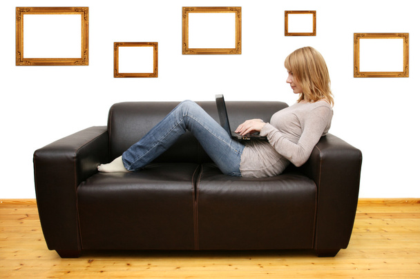 Mladá žena ležící na pohovce a pomocí notebooku - Fotografie, Obrázek