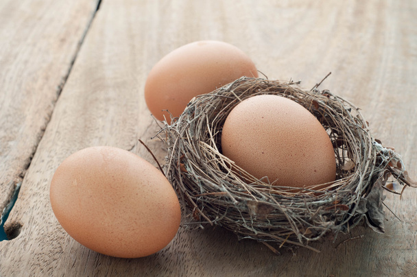 Tre uova su pavimenti in legno e nido
. - Foto, immagini