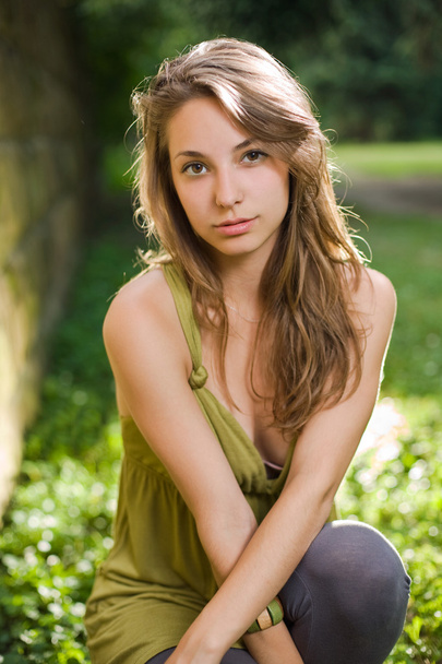 Beautiful young brunette posing in green dress. - 写真・画像