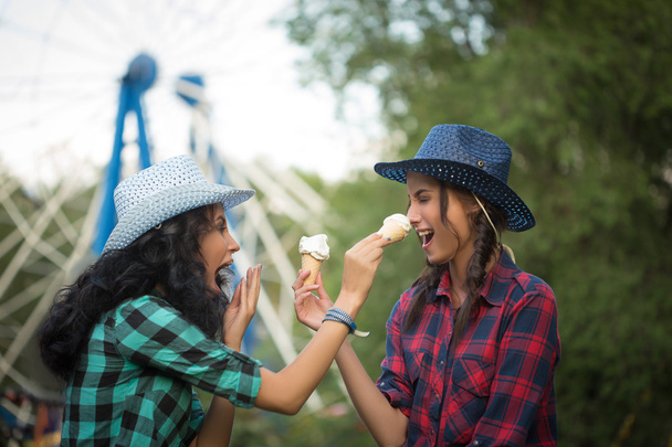 two beautiful girls in cowboy hats eating ice cream - Photo, Image