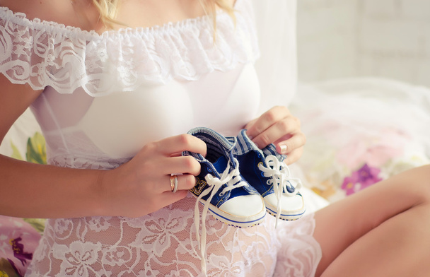 Embarazada holding botines
 - Foto, Imagen