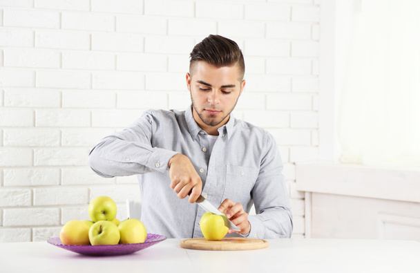 Young man cutting apples, preparing apple juice - Foto, imagen