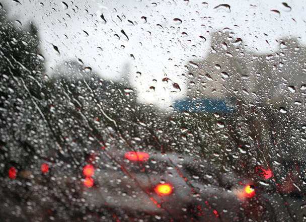 Σπουδαῖον τις σταγόνες του νερού στο αυτοκίνητο παρμπρίζ από το εσωτερικό του αυτοκινήτου στο βροχή σε δρόμο της πόλης - Φωτογραφία, εικόνα