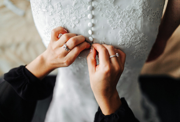 Подружка невесты помогает невесте с платьем
 - Фото, изображение