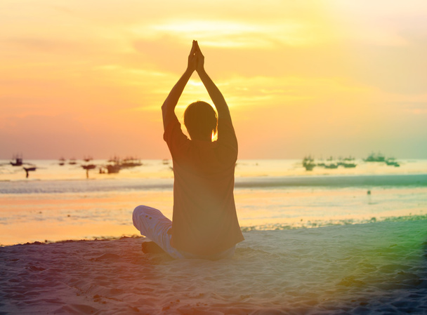 Silhouette de l'homme faisant du yoga à la plage du coucher du soleil
 - Photo, image