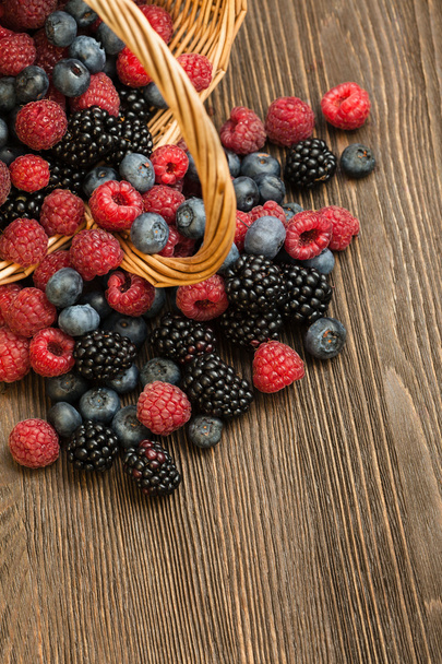 different berries in a basket on a wooden table - Foto, imagen