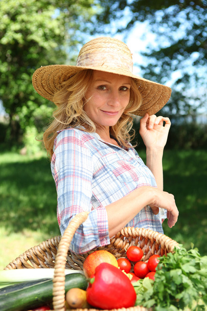 Woman with a straw hat and basket of vegetables. - Фото, изображение