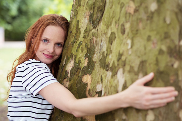 Young Woman Hugging a Huge Tree Trunk - Valokuva, kuva